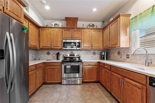 kitchen with stainless steel appliances, brown cabinetry, a sink, and decorative backsplash