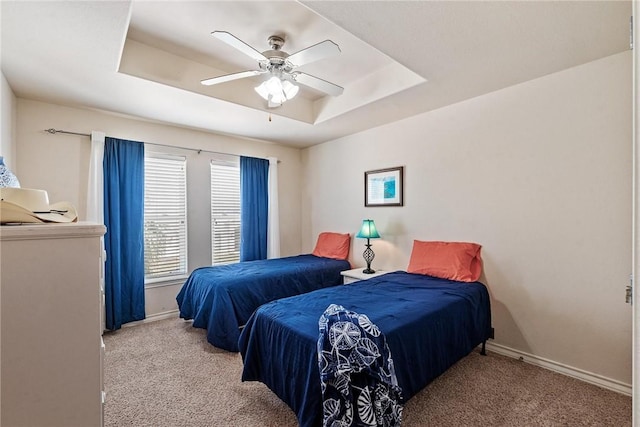 carpeted bedroom with baseboards, a ceiling fan, and a raised ceiling