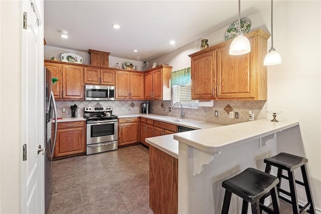 kitchen featuring a peninsula, appliances with stainless steel finishes, a breakfast bar area, and backsplash