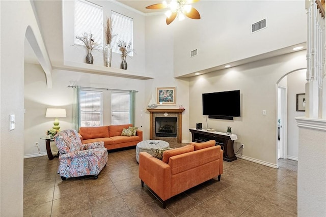 living area with visible vents, a wealth of natural light, a ceiling fan, and arched walkways