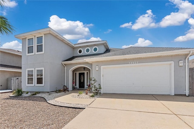 view of front of home with concrete driveway, stucco siding, fence, and a garage