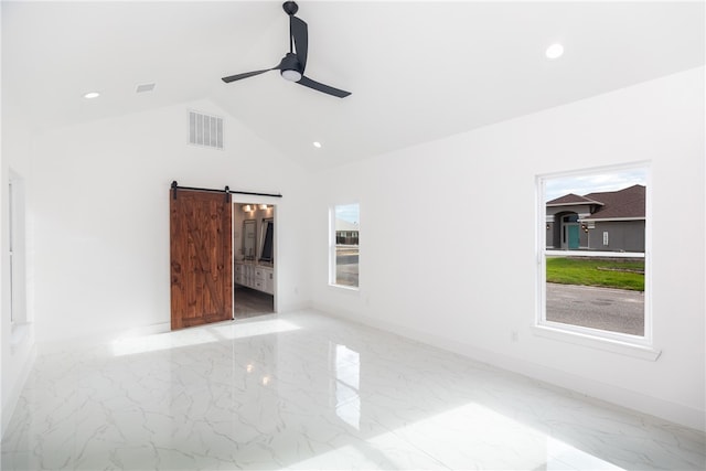 empty room featuring a barn door, ceiling fan, and lofted ceiling