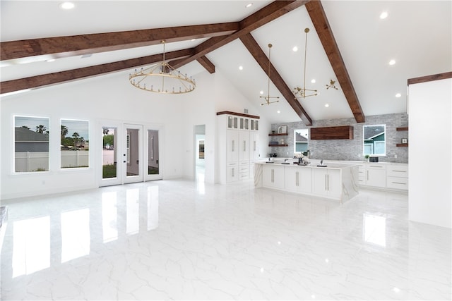 unfurnished living room with beam ceiling, high vaulted ceiling, and a notable chandelier