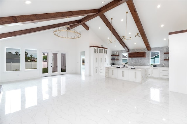 13974 Blackbeard Dr, Corpus Christi, TX 78418 - unfurnished living room with a chandelier, beam ceiling, high vaulted ceiling, light marble finish floors, and french doors