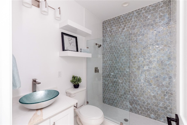 bathroom featuring vanity, toilet, and a tile shower