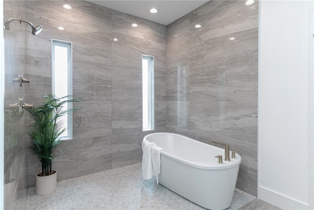 bathroom featuring a bathtub, tile walls, and a healthy amount of sunlight