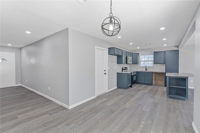 kitchen featuring wood-type flooring, light stone counters, hanging light fixtures, sink, and appliances with stainless steel finishes