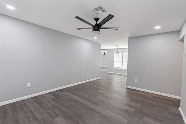 spare room with ceiling fan with notable chandelier and dark hardwood / wood-style floors