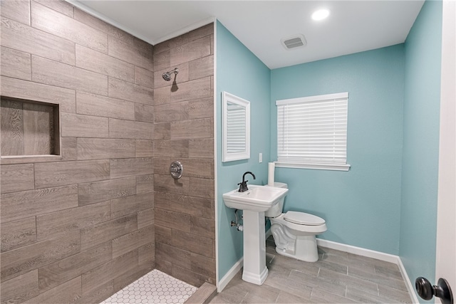 bathroom with toilet, hardwood / wood-style flooring, and a tile shower