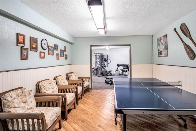 recreation room featuring light hardwood / wood-style flooring and a textured ceiling