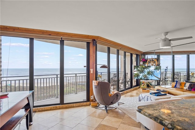 sunroom featuring a view of the beach, ceiling fan, and a water view