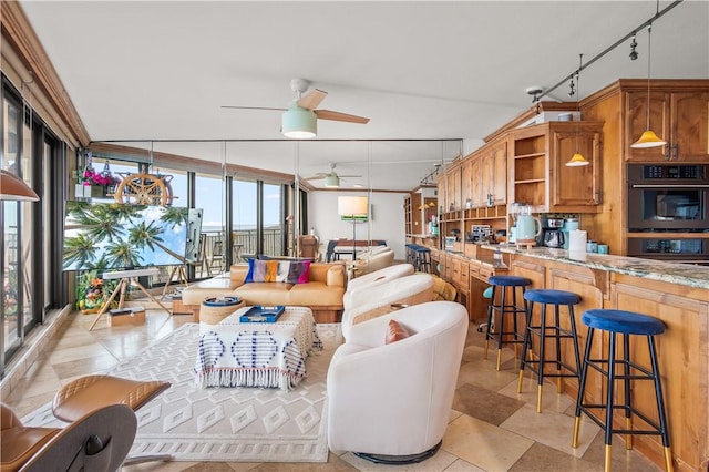 living room with expansive windows, track lighting, and ceiling fan