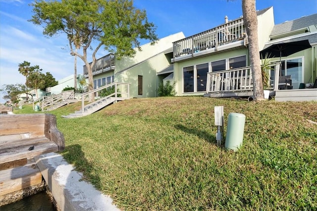 rear view of house with a balcony and a lawn