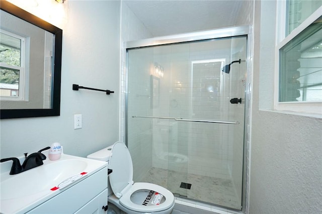 bathroom featuring toilet, a textured wall, a shower stall, and vanity