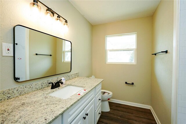 bathroom featuring toilet, wood finished floors, vanity, and baseboards