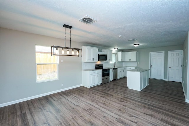 kitchen with visible vents, dark wood-style flooring, stainless steel appliances, light countertops, and a sink