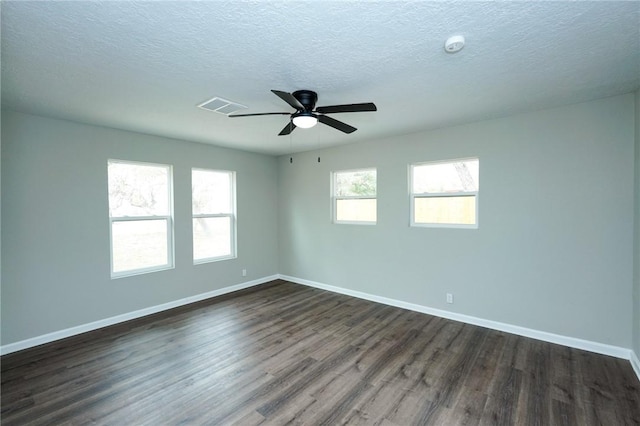 unfurnished room featuring baseboards, a textured ceiling, visible vents, and dark wood-style flooring