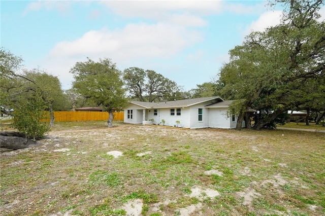 back of property featuring a lawn and fence