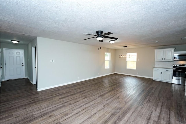 unfurnished living room with a ceiling fan, dark wood-style flooring, a textured ceiling, and baseboards