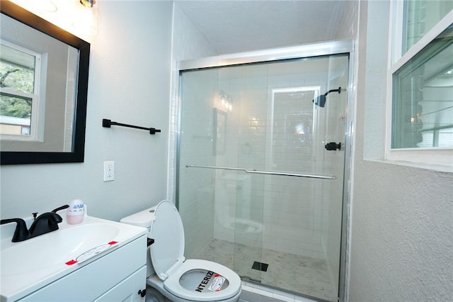 full bath with toilet, a textured wall, a stall shower, and vanity