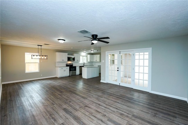 unfurnished living room with ceiling fan, dark wood-style flooring, visible vents, and baseboards