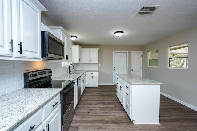 kitchen featuring appliances with stainless steel finishes, dark wood-style flooring, visible vents, and a center island