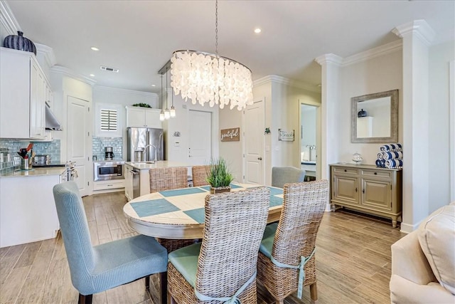 dining space featuring light hardwood / wood-style floors, crown molding, and a chandelier