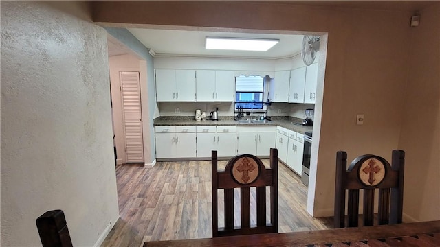 kitchen featuring white cabinets, light hardwood / wood-style floors, and stainless steel range oven