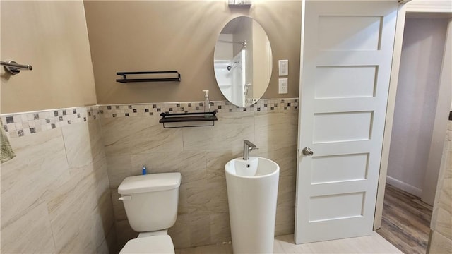 bathroom with hardwood / wood-style flooring, toilet, and tile walls