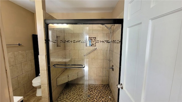 bathroom featuring a shower with shower door and toilet