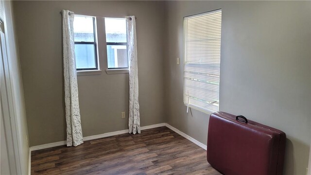 spare room with dark wood-type flooring and a healthy amount of sunlight