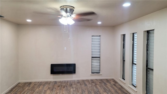 spare room featuring dark hardwood / wood-style floors, heating unit, and a healthy amount of sunlight