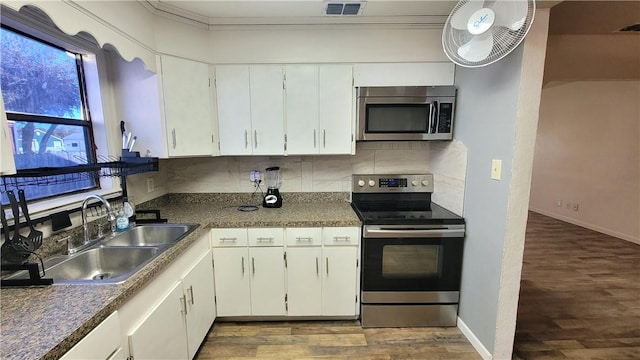 kitchen featuring white cabinetry, sink, stainless steel appliances, tasteful backsplash, and hardwood / wood-style floors