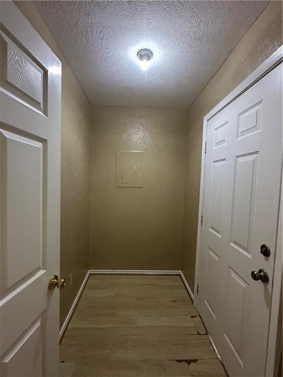 interior space featuring light wood-type flooring, a textured ceiling, and electric panel