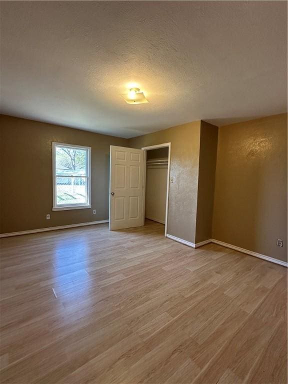 616 Hall St Unit A & B, Sinton, TX 78387 - unfurnished bedroom with light wood-style flooring, baseboards, a closet, and a textured ceiling
