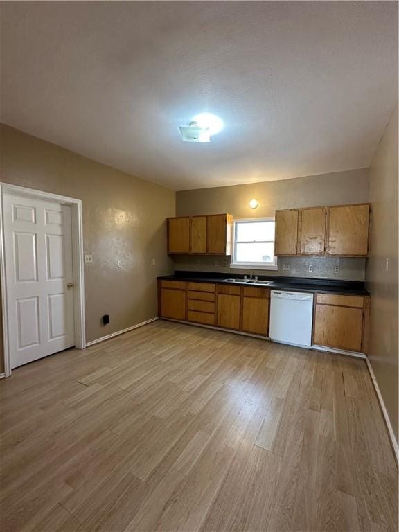 kitchen with tasteful backsplash, dishwasher, sink, and light hardwood / wood-style floors