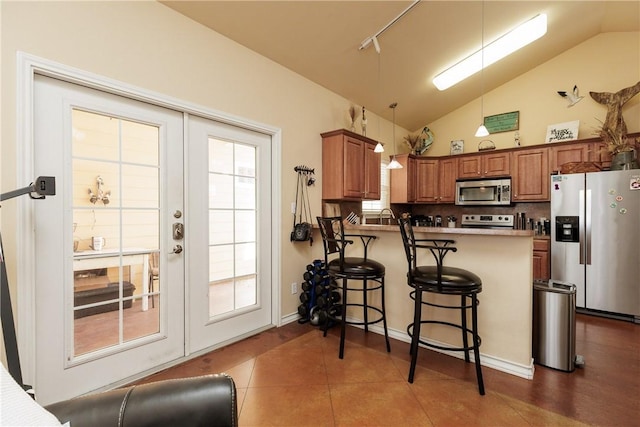 kitchen with a peninsula, appliances with stainless steel finishes, brown cabinets, and a breakfast bar area