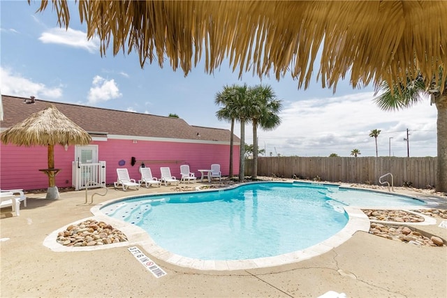 community pool with a patio area and fence