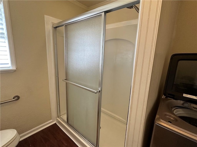 230 Lola Johnson, Corpus Christi, TX 78418 - bathroom with toilet, wood finished floors, a stall shower, stacked washer / drying machine, and baseboards