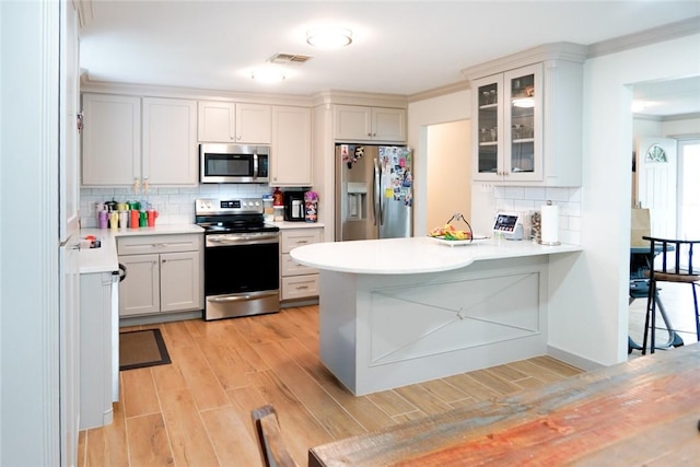 4625 Harney Rd, Corpus Christi, TX 78410 - kitchen featuring stainless steel appliances, light wood-type flooring, light countertops, tasteful backsplash, and glass insert cabinets
