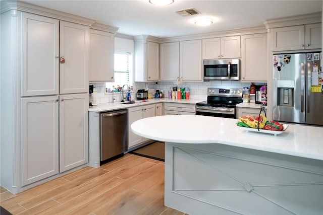4625 Harney Rd, Corpus Christi, TX 78410 - kitchen featuring stainless steel appliances, light wood-type flooring, decorative backsplash, and light countertops