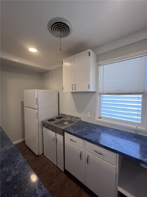 kitchen with white cabinetry, sink, and white refrigerator