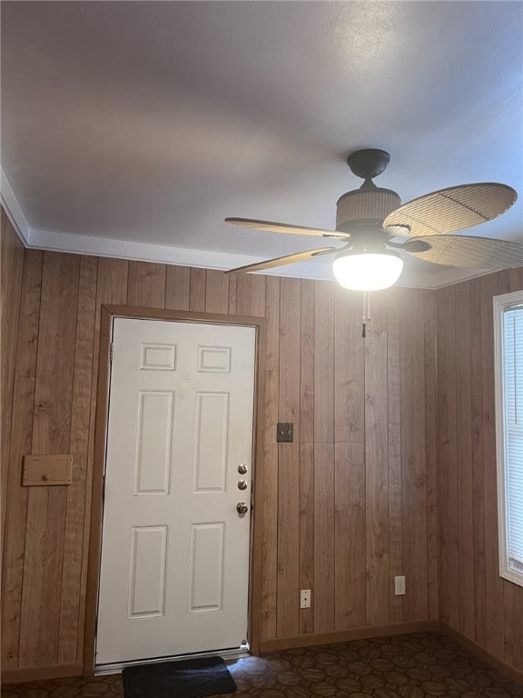 interior space with ceiling fan and wood walls