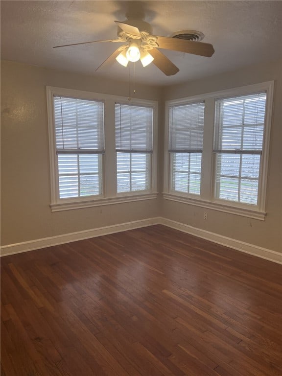 spare room with ceiling fan, dark hardwood / wood-style floors, and a healthy amount of sunlight