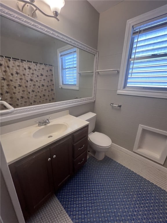 bathroom with tile walls, toilet, vanity, and curtained shower