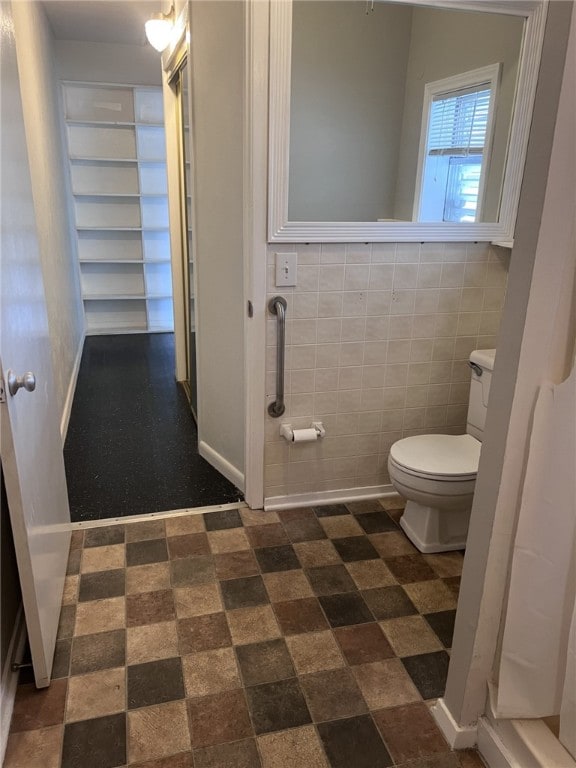 bathroom with toilet and tile walls