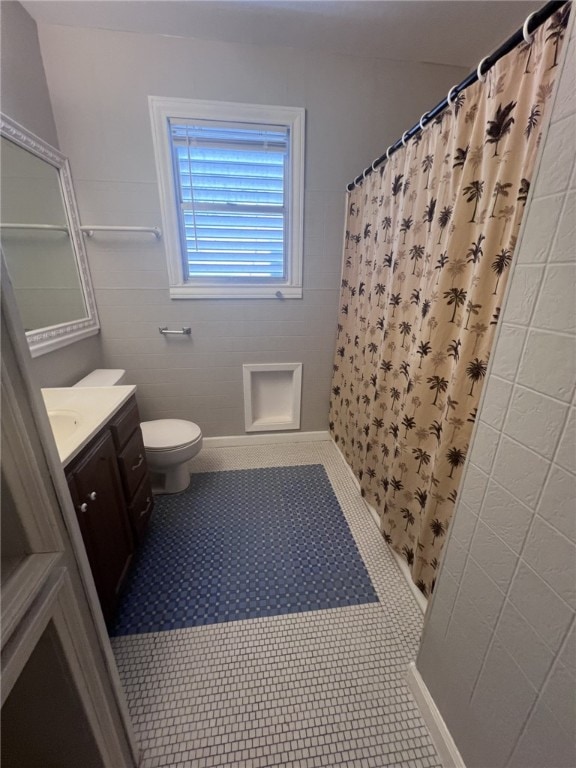 bathroom with tile patterned floors, a shower with curtain, toilet, tile walls, and vanity