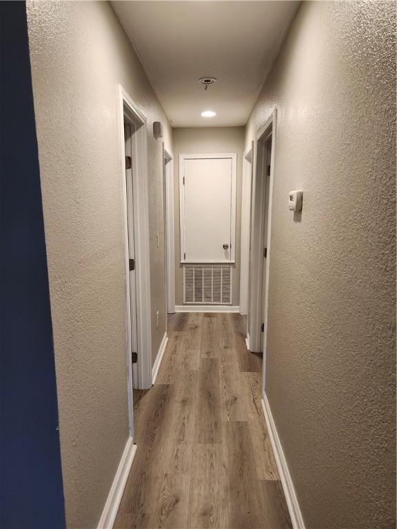 413 S 13th St, Aransas Pass, TX 78336 - hallway featuring wood finished floors, a textured wall, and baseboards