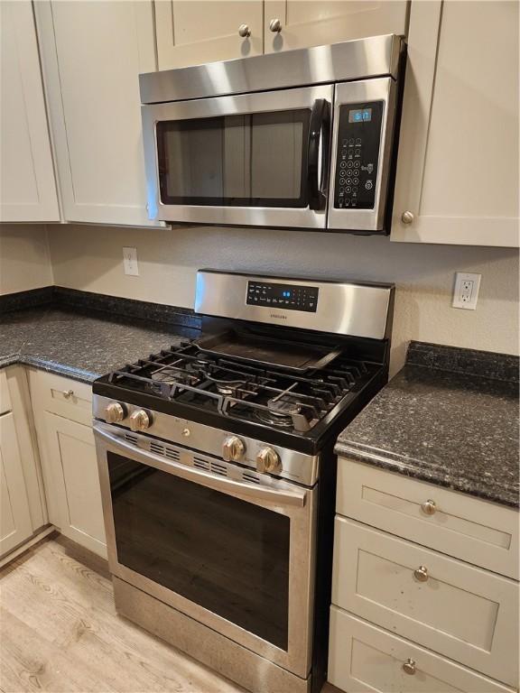 413 S 13th St, Aransas Pass, TX 78336 - kitchen featuring stainless steel appliances, light wood finished floors, and dark stone counters