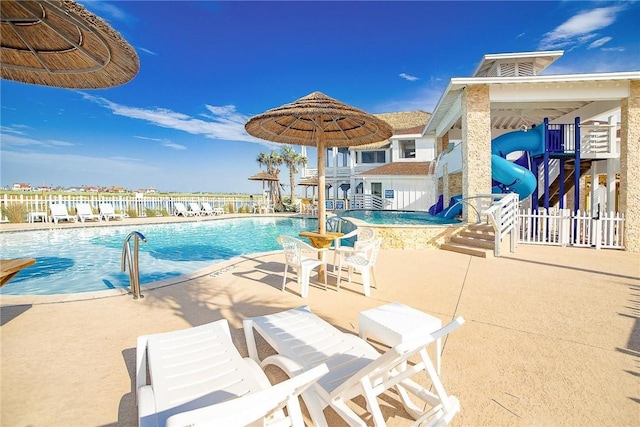 view of pool with a water slide and a patio area